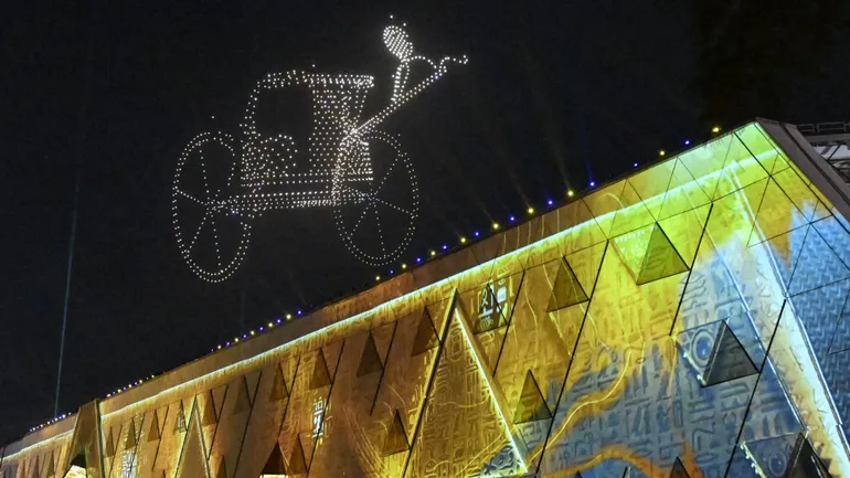 Des effets lumineux représentant l'un des chars de l'ancien roi égyptien Toutânkhamon illuminent le ciel lors de la cérémonie d'inauguration du Grand Musée égyptien (GEM) à Gizeh, dans la banlieue sud-ouest de la capitale Le Caire, le 1er novembre 2025.