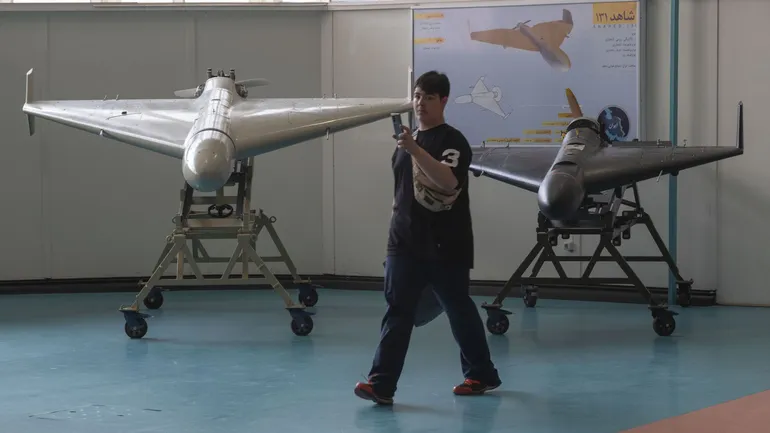 Un écolier iranien prend des photos avec son téléphone portable devant les drones Shahed-136 (à gauche) et Shahed-131 lors de sa visite au Parc aérospatial national du Corps des gardiens de la révolution islamique (CGRI) à l’ouest de Téhéran, le 11 octobr