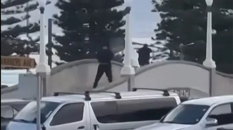 Cette capture d'écran tirée d'une vidéo fournie par Timothy Brant-Coles montre deux hommes armés vêtus de noir tirant plusieurs coups de feu sur un pont à Bondi Beach, à Sydney, le 14 décembre 2025.
