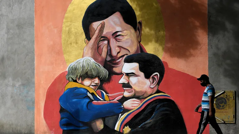 Un homme passe devant une fresque murale représentant le défunt président vénézuélien Hugo Chavez (au centre) saluant et le président vénézuélien Nicolas Maduro (à droite) tenant un enfant dans ses bras, à Caracas, le 9 décembre 2020.